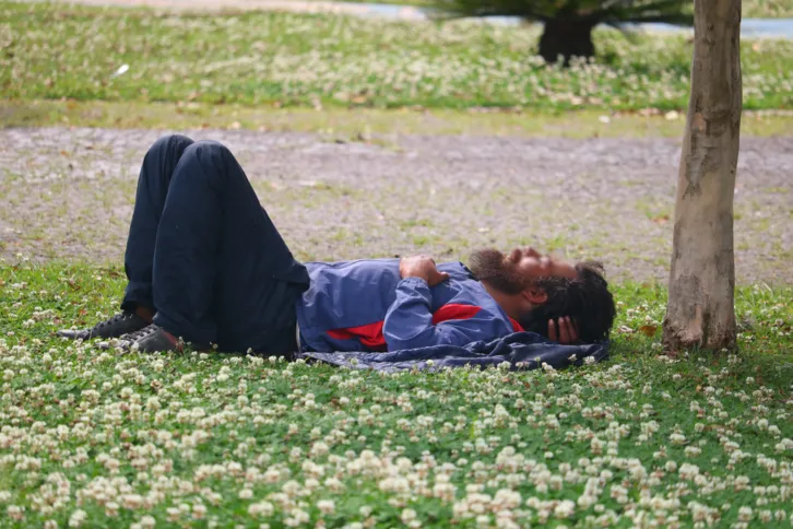 Morador em situação de rua deitado nas proximidades do Parque Ambiental.